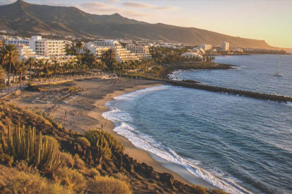 A coastal town in north Tenerife with green hills behind it