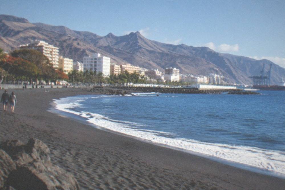 A quiet beach with dark sand and a view of the Atlantic in Tenerife
