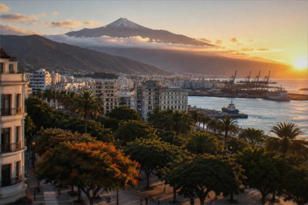 A snow-dusted volcanic peak above a layer of cloud at sunrise