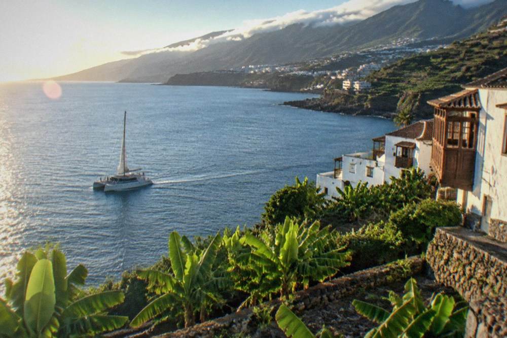 A catamaran under way on calm blue water near the Tenerife south coast