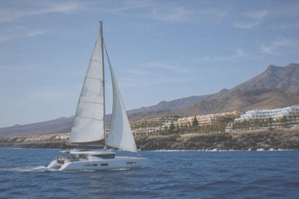 A catamaran under sail along Tenerife's southwest coast in bright summer conditions