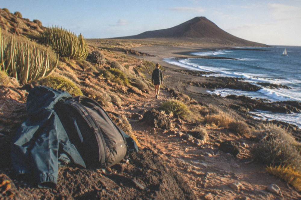 A hiking jacket and daypack resting on volcanic rock at altitude
