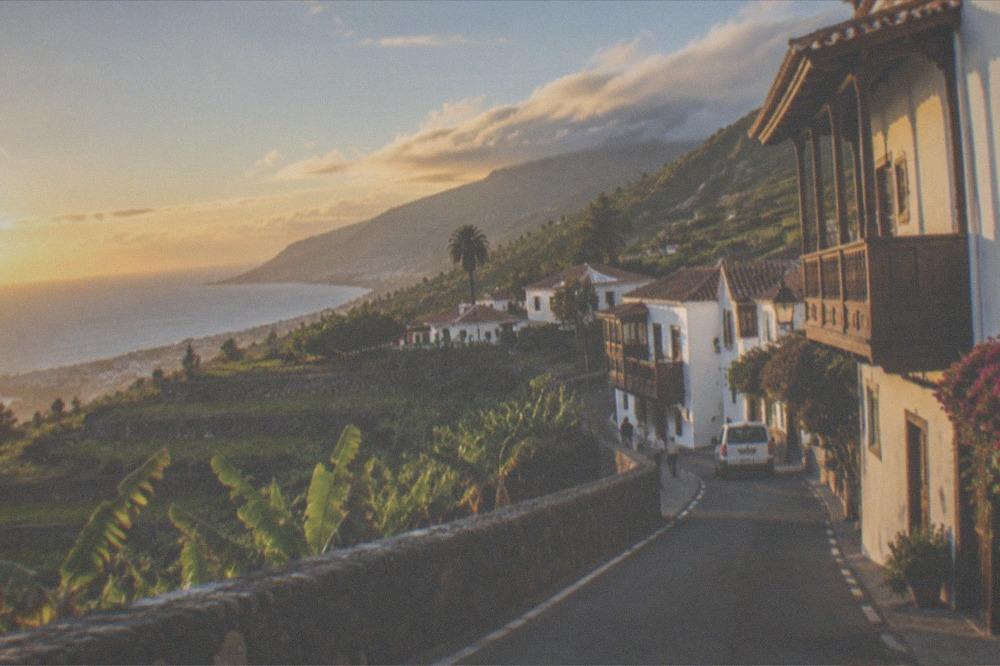 A coastal road in south Tenerife with sunshine on the sea and green hills in the background