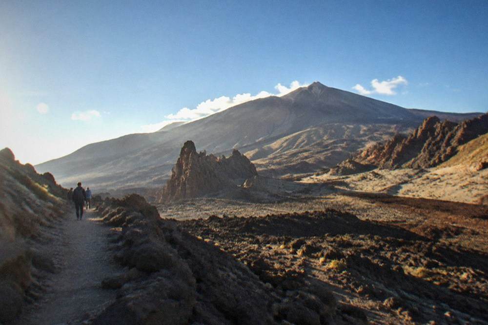 The volcanic slopes of Mount Teide with thin clouds above the ridge