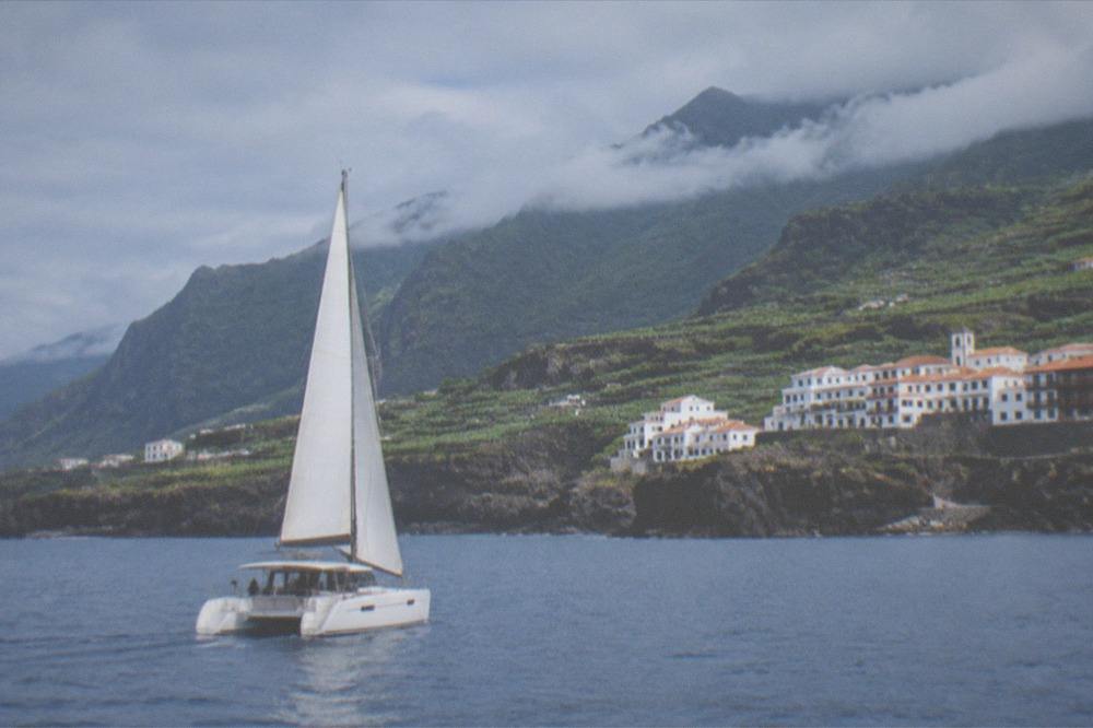 A catamaran under sail on calm blue water near the Tenerife coastline