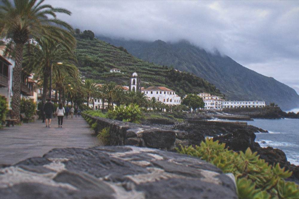A promenade in a Tenerife resort town with palm trees and people walking in the evening