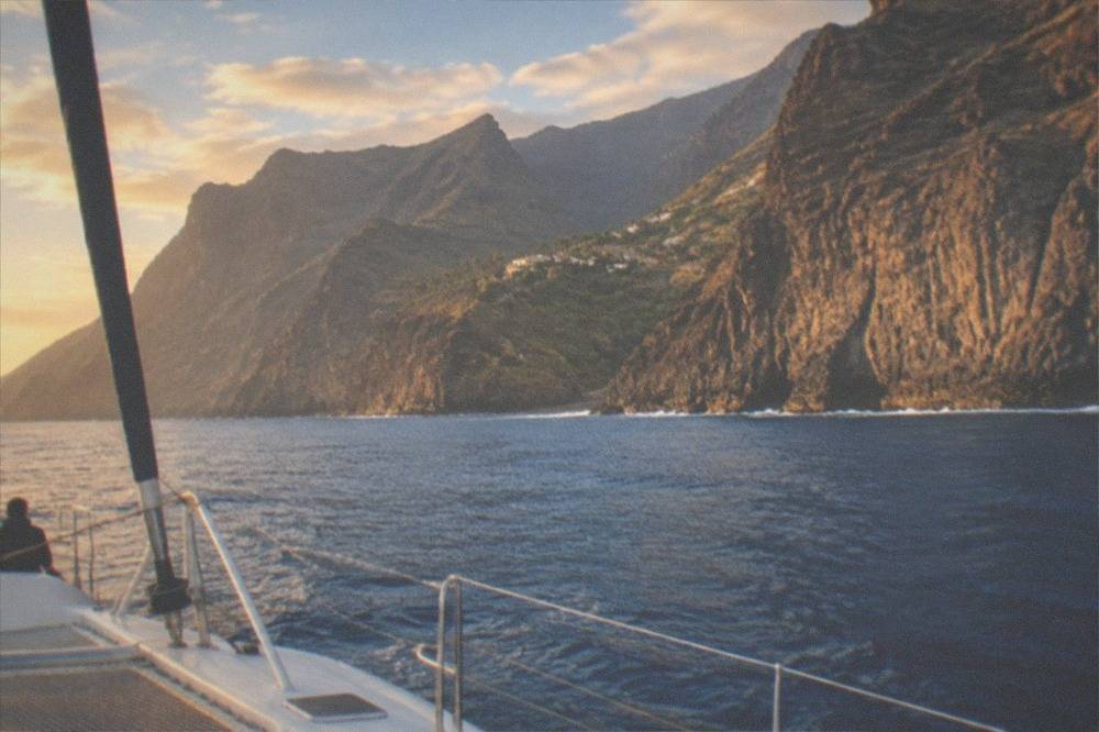 A catamaran under way on calm blue water near the tall cliffs of Los Gigantes