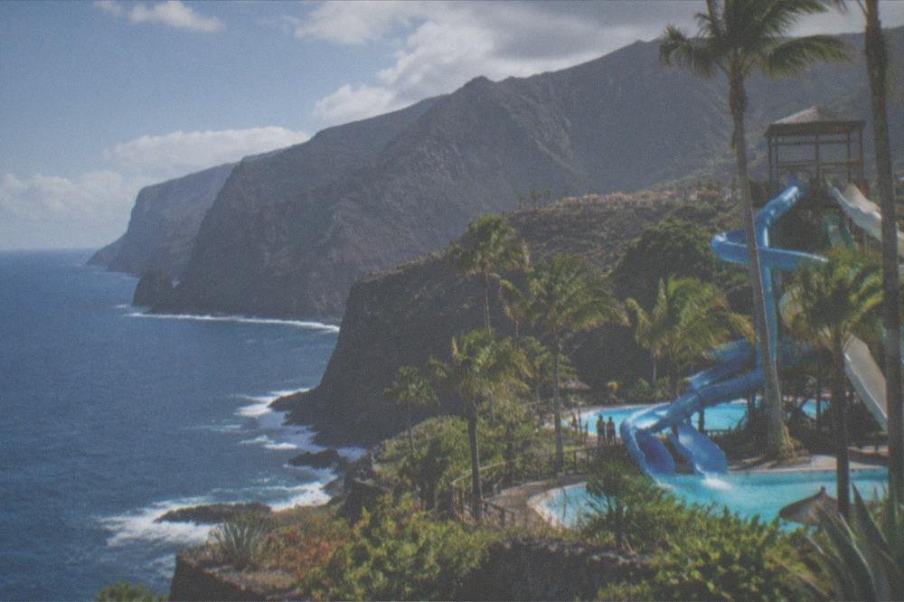 A water slide tower and turquoise pools of a large water park under palm trees
