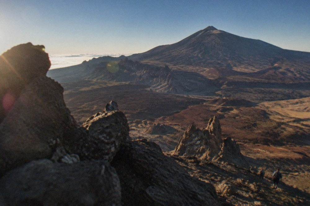 A wide view across the Teide caldera, the volcanic cone rising above rust and black lava fields under a deep blue sky