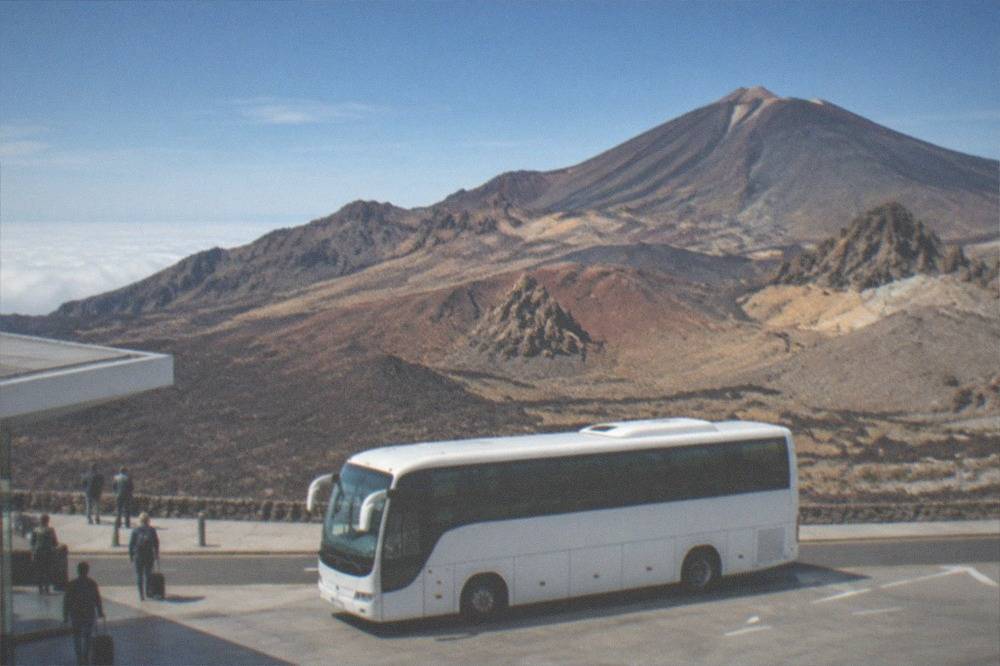 An island bus parked outside a Tenerife airport terminal under a blue sky
