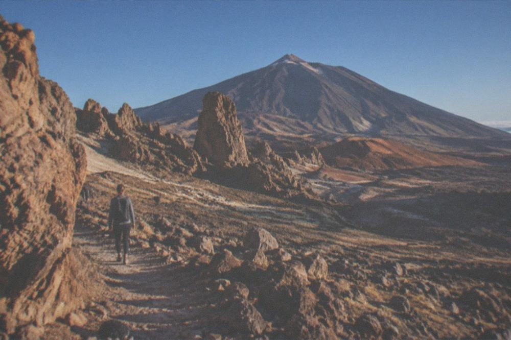 Rock formations in Teide National Park with a volcanic cone and a clear sky above the ridge