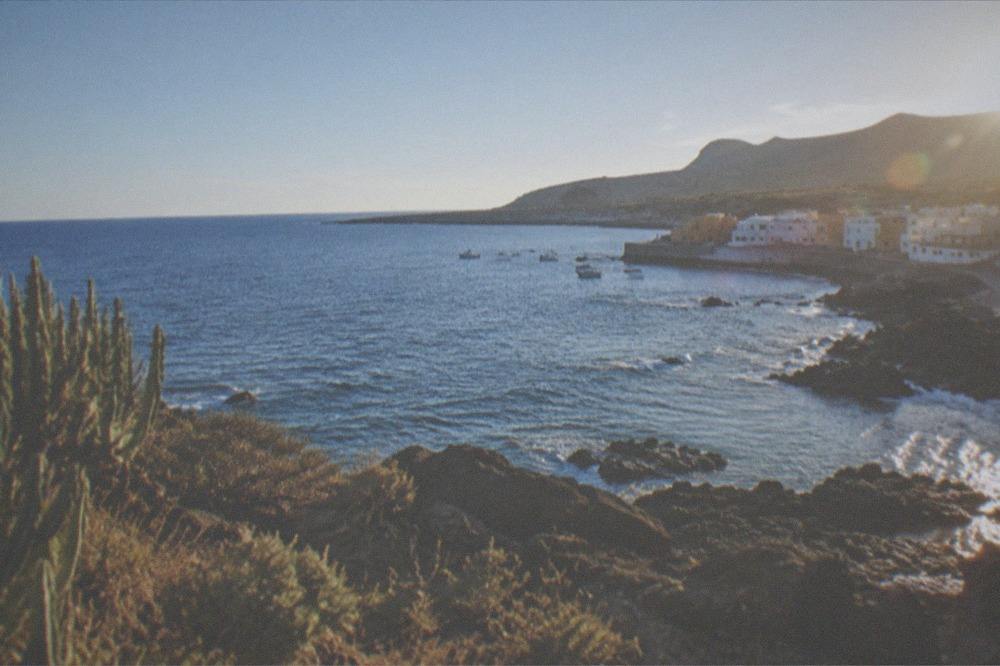 A coastal view at Los Abrigos in south Tenerife with calm blue water and a rocky shoreline