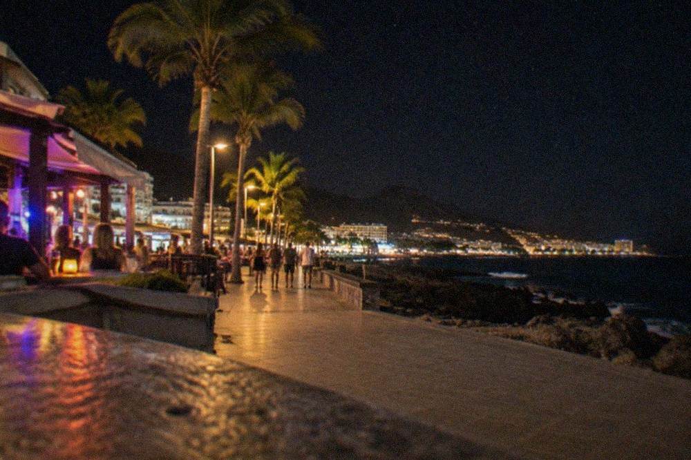 A night-time street of illuminated bars and music venues in a Tenerife resort