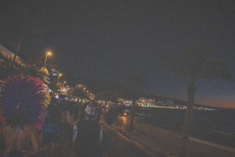 A carnival crowd in costumes at night in a city street
