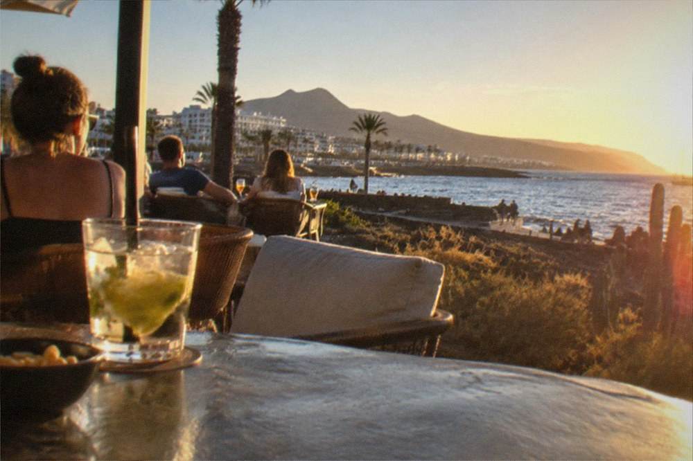 People at an outdoor terrace bar in warm evening light by the sea in Tenerife