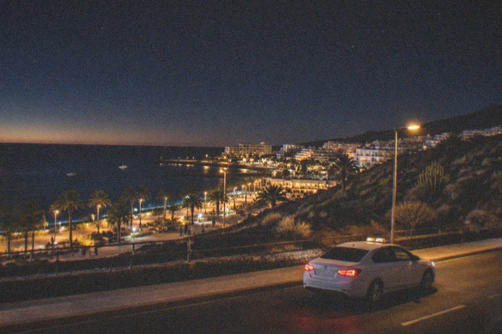 A white taxi waiting on a lit street at night in a Tenerife town