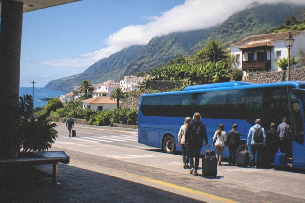A blue island bus waiting at an airport stop with passengers and luggage