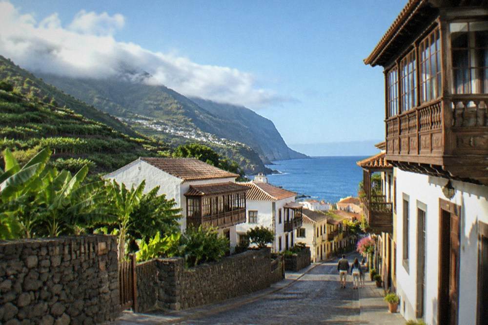 A quiet sunlit street of traditional balconied wooden houses in a northern Tenerife town