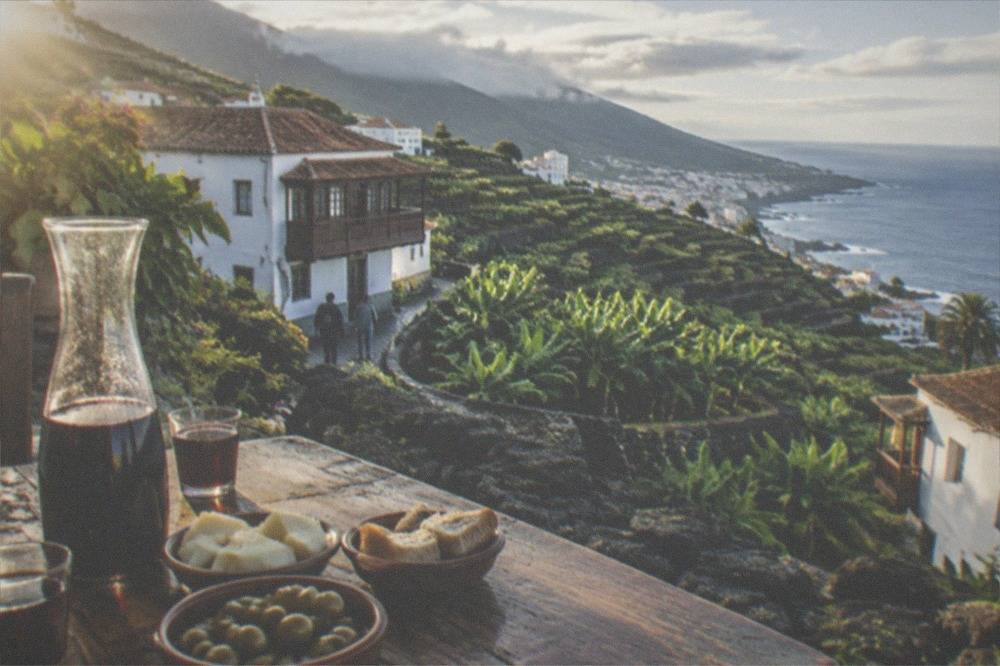 Rough local volcanic wine poured into small glasses beside simple dishes on a rustic table