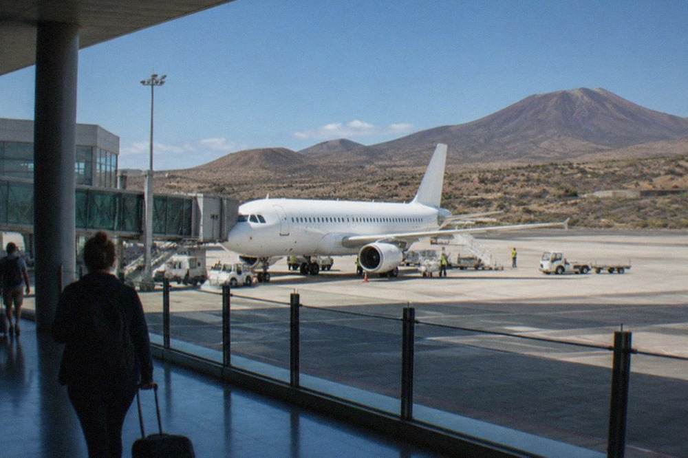 A modern airport terminal building under a clear blue sky in an arid inland plain