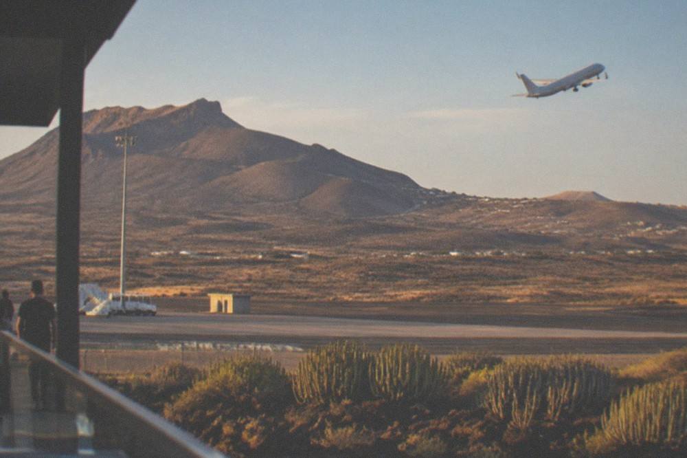 An aeroplane climbing away over the coastline of southern Tenerife in evening light