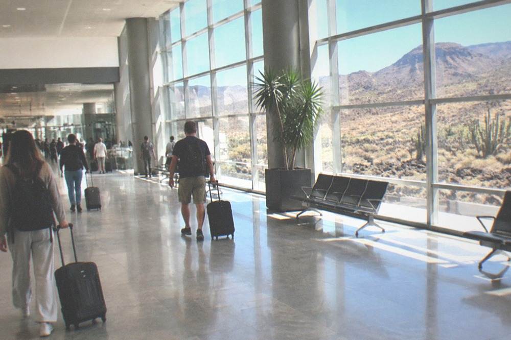 Passengers with suitcases walking through a bright airport arrivals hall