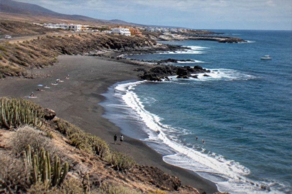 A wide sandy beach at Los Abrigos on the dry southern coast under scattered clouds
