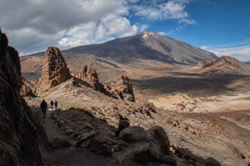 A volcanic landscape of reddish rock formations under a wide sky high on Mount Teide