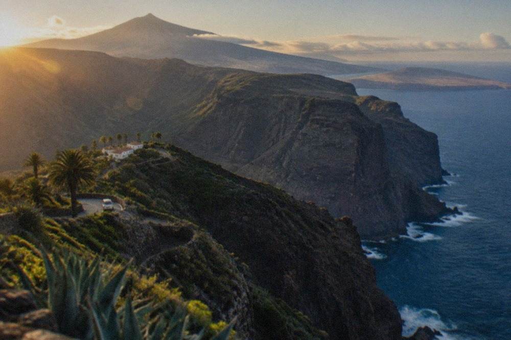 Two Canary islands seen from the air, one green and mountainous with a volcanic peak, the other flat with long pale beaches