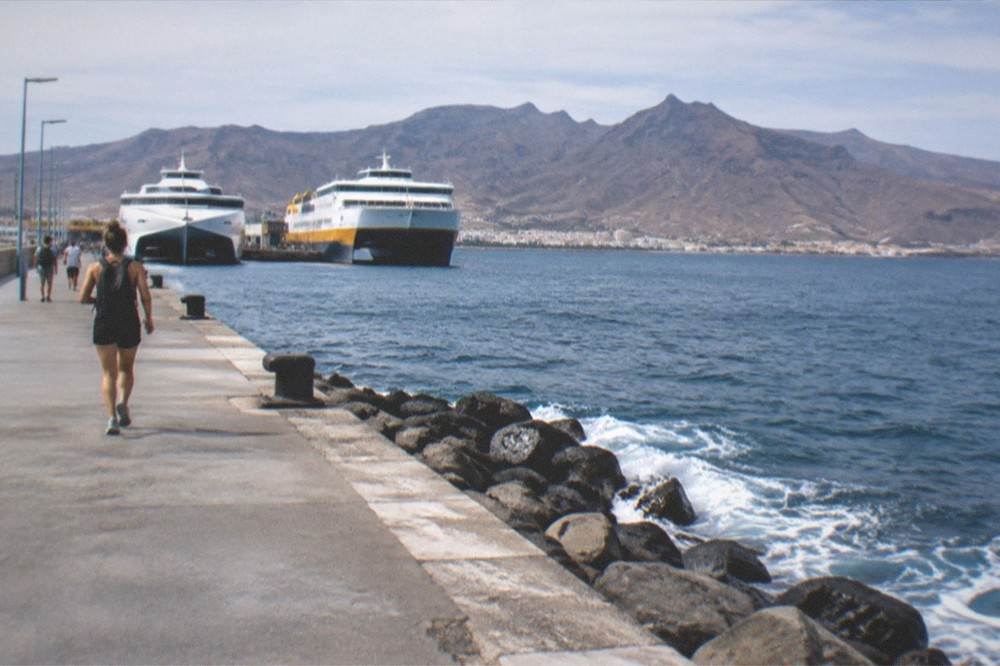 Two ferries moored side by side at Los Cristianos harbour with mountains in the distance
