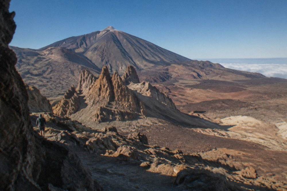 A volcanic mountain rising above clouds on a Canary Island coastline