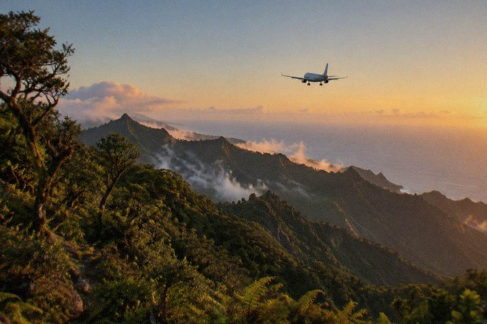 A passenger aircraft on final approach over rocky island terrain towards a coastal runway