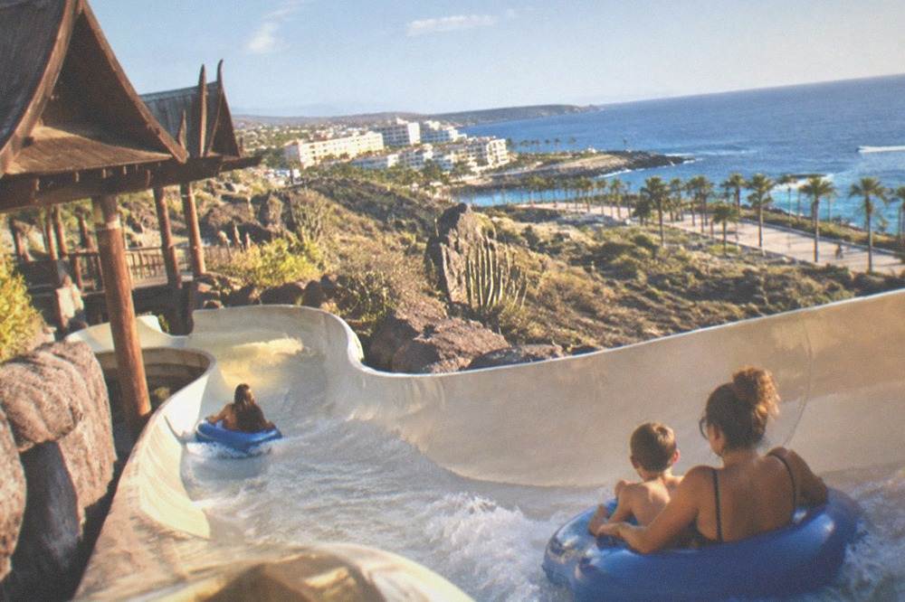 Families on a water slide at a Thai-themed water park in Tenerife under a sunny sky