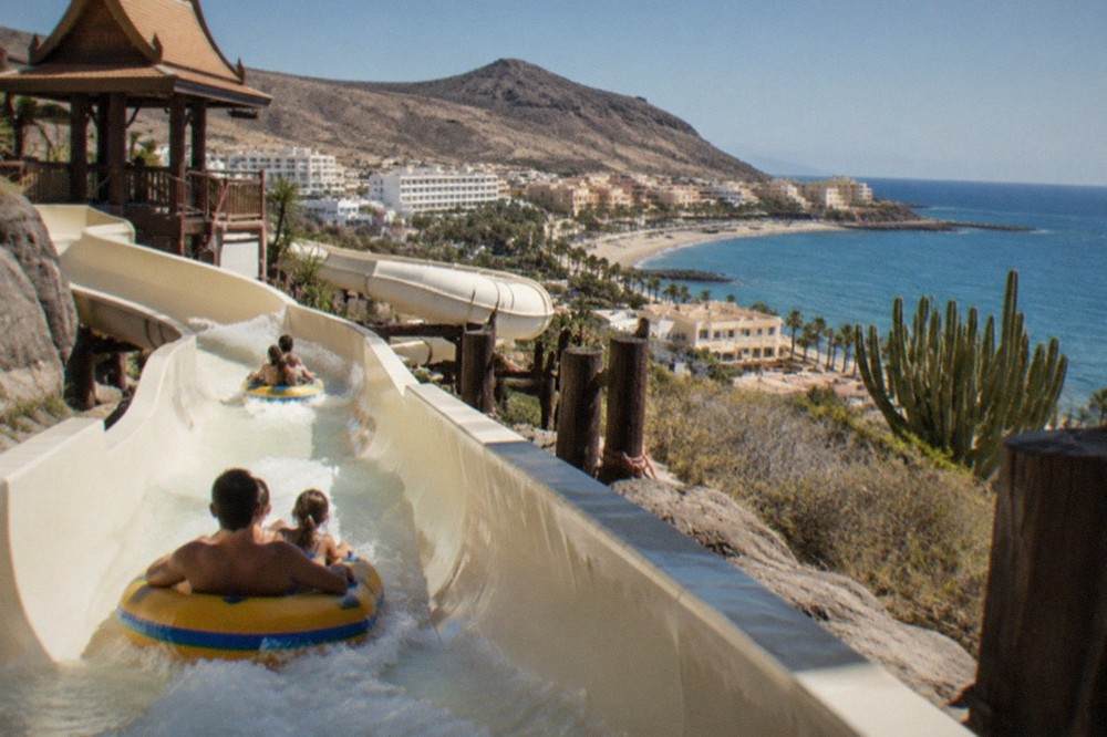 Families on rafts descending a water slide at a Thai-themed water park in Tenerife