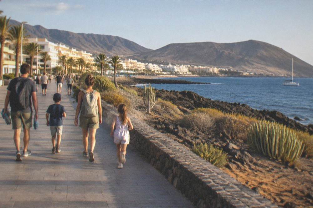 Parents and children planning a day out with a map at a cafe table in a Tenerife resort