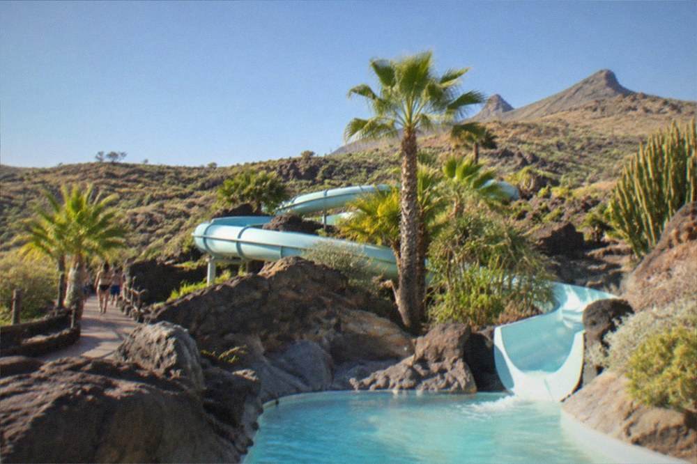A water park slide winding between rocks and tropical planting