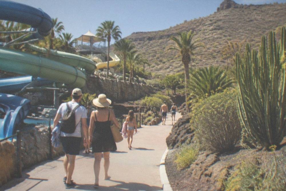 A family walking along a path between water slides and tropical planting
