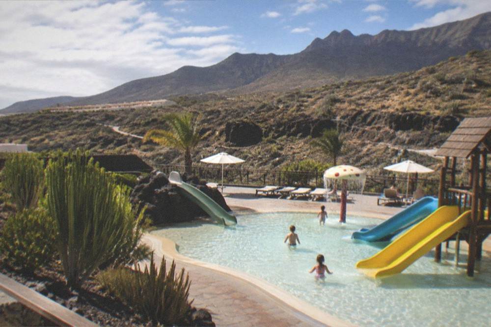 Children splashing in a shallow pool with small water slides