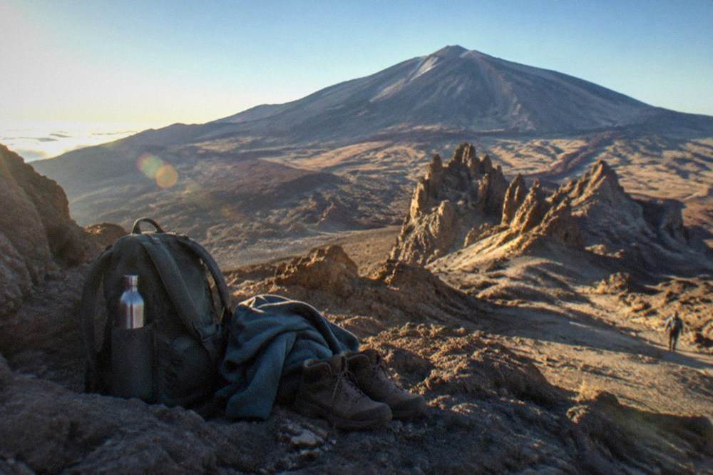 A day rucksack with a water bottle, a fleece and hiking boots arranged beside it