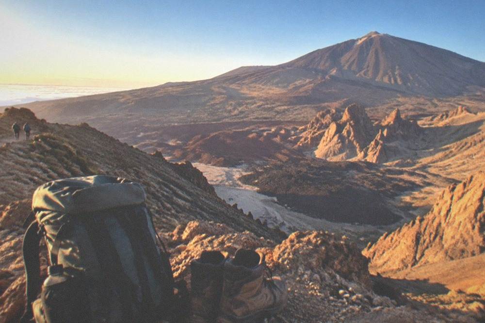 Hiking boots and a packed rucksack on rocky volcanic ground