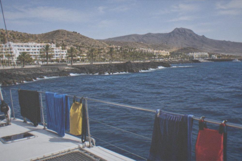 A catamaran deck at Puerto Colon with towels and dry bags clipped along the rail in sunshine