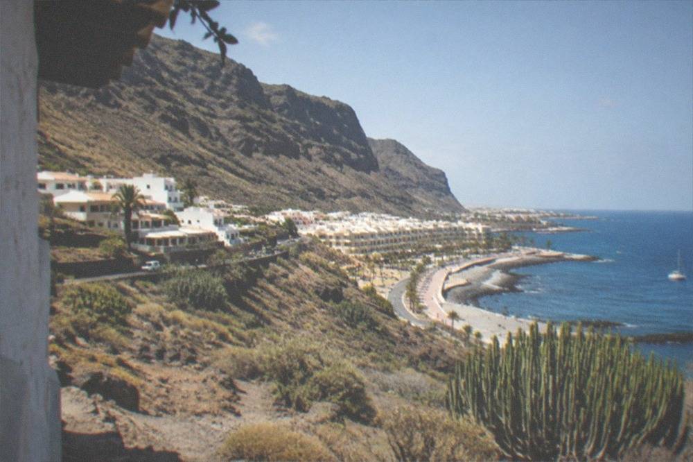 A small village of white houses beneath steep green cliffs near the coast