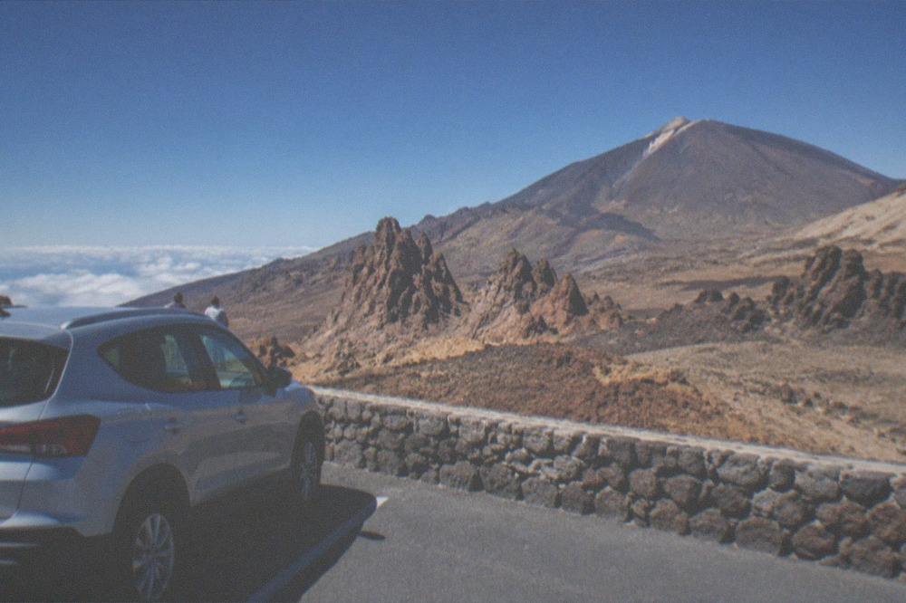 A rental car parked at a viewpoint above the cloud line on Mount Teide