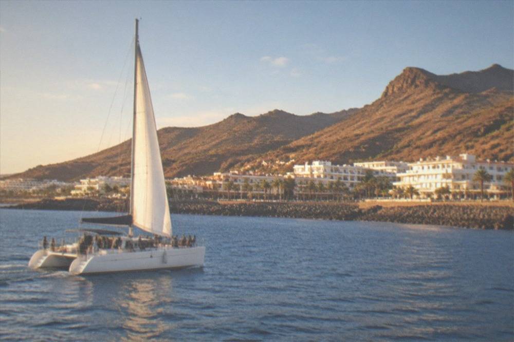 A catamaran with passengers sailing on calm water near the Tenerife coast