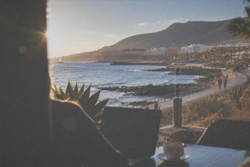 A laptop and coffee on a terrace table overlooking the sea in Tenerife