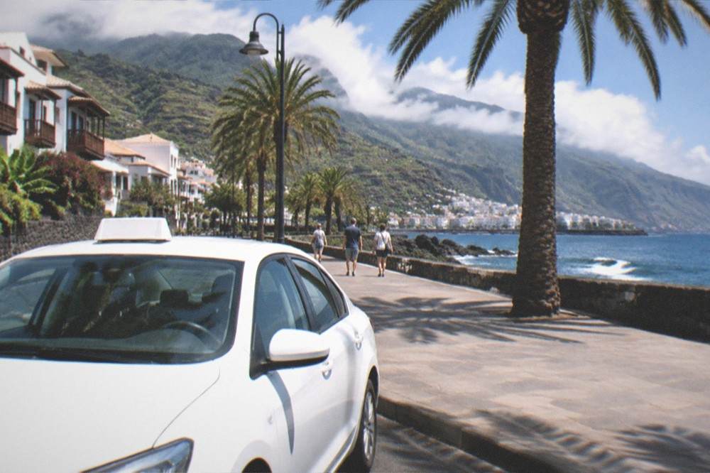A white taxi and palm trees on a seafront promenade in Puerto de la Cruz