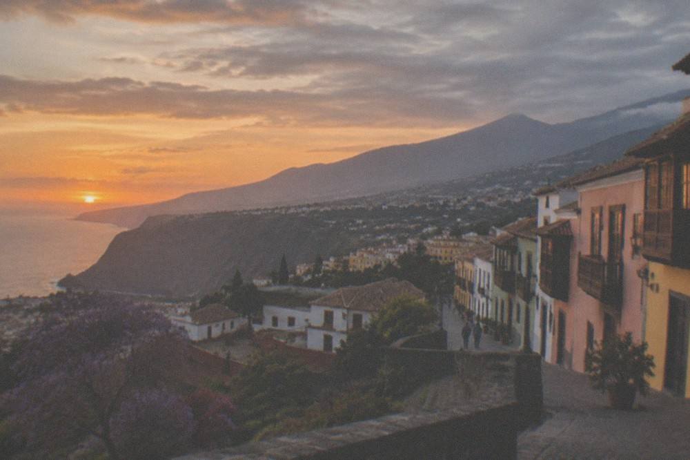 A wide view of Tenerife coastline with beaches, cliffs and distant mountains at sunset