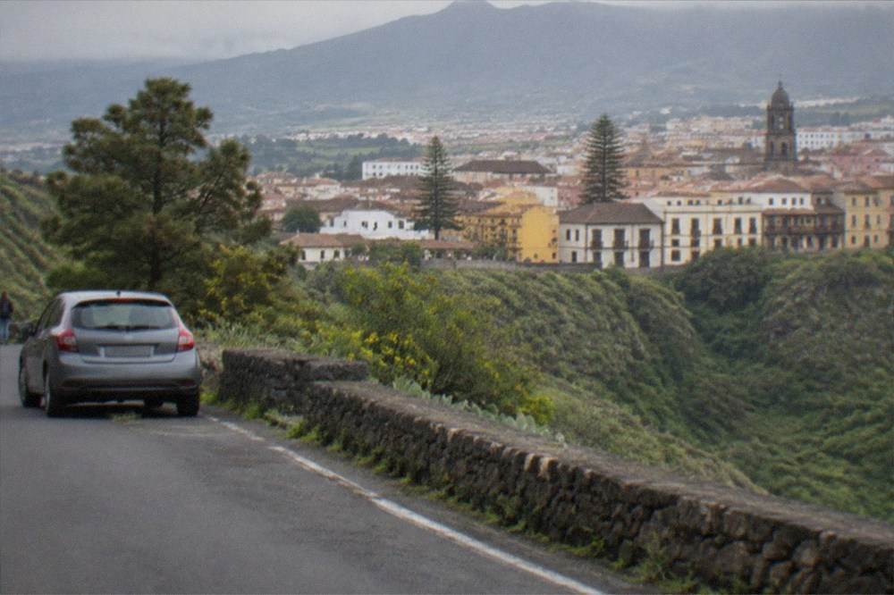 A winding mountain road with a parked car overlooking a deep valley