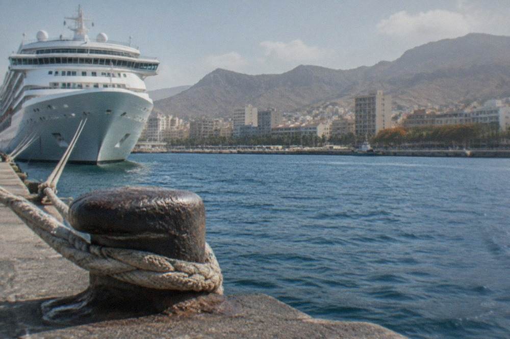 A large cruise ship tied alongside a harbour in Santa Cruz de Tenerife with the city behind it
