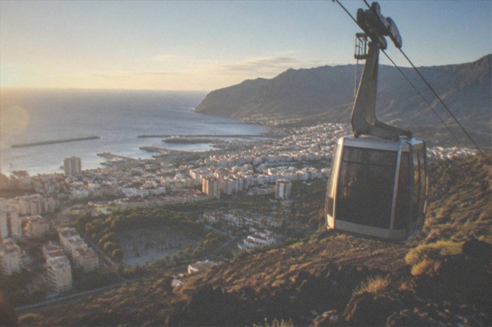 A cable car cabin travelling up a rocky volcanic slope toward the upper station on Mount Teide